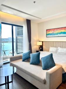 1 dormitorio con 1 cama y 1 sofá con almohadas azules en Em Apartment - Ocean and Lighthouse View, Sapphire Residence S2, en Ha Long