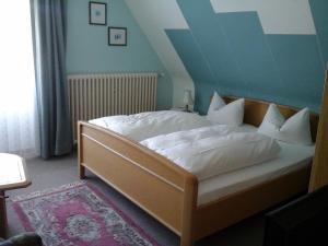 Schlafzimmer mit einem Bett mit weißer Bettwäsche und Kissen in der Unterkunft Hotel Amselhof in Bispingen