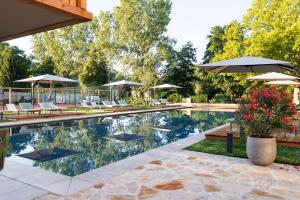 a pool with chairs and umbrellas in a yard at Weinlandhof in Gamlitz