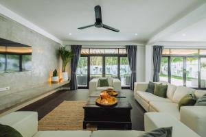 a living room with white furniture and a ceiling fan at Eden Villa A Tropical Paradise Pool Villa in Rawai Beach
