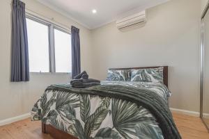 a bedroom with a bed with a green and white blanket at Terrific Townhouse 3x2 in CBD in Port Hedland