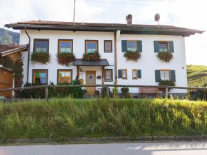 a white house with flowers on the windows at Alpenapartment mit Garten in Trauchgau +32 photos