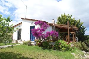 a white house with purple flowers in the yard at O Ioannis in Kritinía