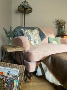 ein Wohnzimmer mit einem rosa Sofa und einem Tisch in der Unterkunft The Old Dairy Cottage in Gainford