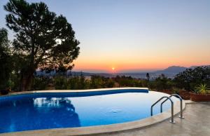 une piscine avec un coucher de soleil en arrière-plan dans l'établissement The Regency Cottage, à İslâmlar 10 autres photos