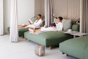 two women sitting on couches in a hotel room reading at Weinlandhof in Gamlitz