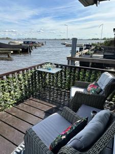 a patio with chairs and a table and water at Woonboot De Witte loosdrechtse plassen in Loosdrecht