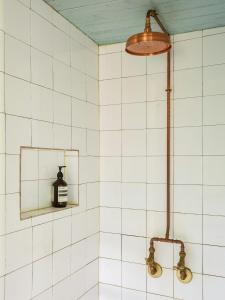 a shower in a white tiled bathroom with a bottle of alcohol at Charming Apartment In Artists Home From 1899 in Lönsboda