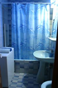 a bathroom with a blue shower curtain and a sink at Apartament Ultra central Style in Bacău