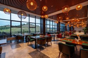 een restaurant met tafels en stoelen en grote ramen bij Blue Spot Resort in Yoliin Hural