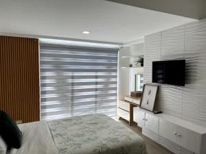 a bedroom with a bed and a window with a television at Tropical Zen Modern Minimalist in Sampong