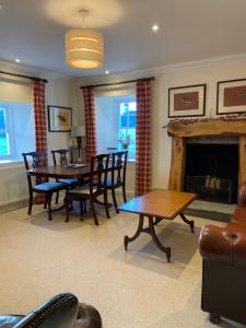 un salon avec une table et des chaises et une cheminée dans l'établissement Fordie West Cottage, à Comrie