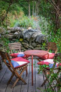 a red table and chairs and a stone wall at Natural Riverside Retreat In Tiglieto in Tiglieto
