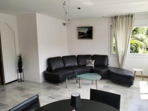a living room with a black leather couch and tables at Villa Caslano in Caslano