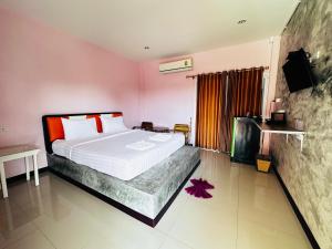 a bedroom with a bed with white sheets and red pillows at พี เค ซี รีสอร์ท in Prakhon Chai