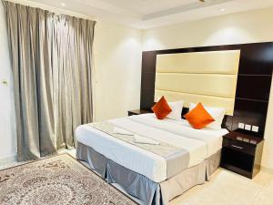 Una habitación de hotel con una cama grande con almohadas naranjas. en الياس التميز للشقق المخدومة, en Yeda 72 fotos más