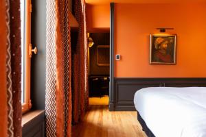 a bedroom with orange walls and a bed and a mirror at Hôtel La Particulière in Caen