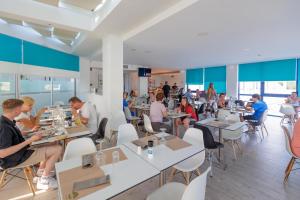 a group of people sitting at tables in a restaurant at Nasos Hotel & Resort in Moraitika