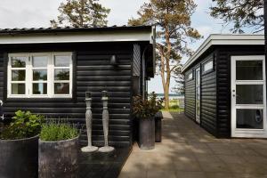 a black tiny house with a porch at Holiday Home With Fjord Views Near Kyndby in Jægerspris