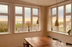 a dining room with a table and four windows at Wooden House With Fjord Views In Hundested in Hundested +12 photos