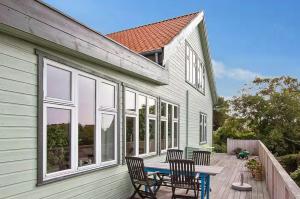 a house with a table and chairs on a deck at Wooden House With Fjord Views In Hundested in Hundested