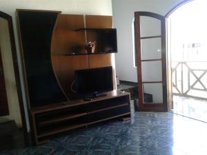 a living room with a television on a wooden entertainment center at Morada Mar e Sol in Arraial do Cabo