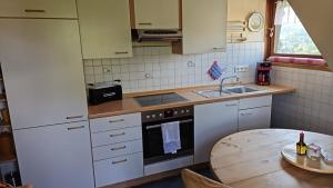 a kitchen with white cabinets and a table with a sink at Ferienwohnung Am Pfaffenberg in Weilmünster +7 photos