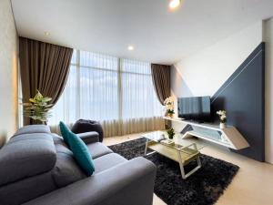 a living room with a gray couch and a tv at The Luxury Penthouse KLCC in Kuala Lumpur