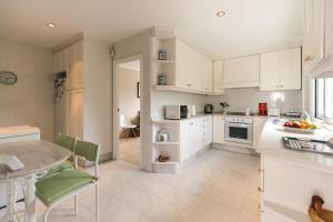 a kitchen with white cabinets and a table at Chalet Veiga da Area in Combarro
