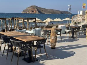 eine Gruppe von Tischen und Stühlen am Meer in der Unterkunft Τhe Noverian Antama Organic Beach Resort Chania in Agia Marina