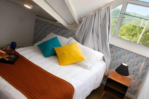 a bedroom with a bed with colorful pillows and a window at Apartamentos estilo loft pertinho da rota do vinho in São Roque