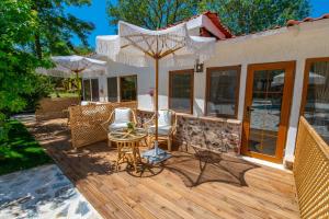 a wooden deck with chairs and an umbrella at VODİNA LOUNGE SUİTEs in Kayakoy