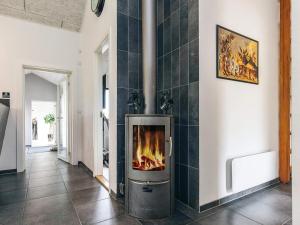 a fireplace in a room with a tile wall at 5 star holiday home in Brovst in Brovst