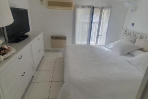 una camera da letto bianca con un letto e una televisione di Detached house with 3 pools a Cogolin Altre 5 foto