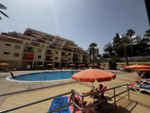 a group of people sitting under an umbrella near a swimming pool at Tagora del Guayero in Los Cristianos