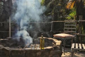 a bottle of wine on a stone table with smoke at Yellowwood Forest Eco Retreat in Morganʼs Bay