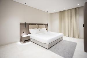 a white bedroom with a bed and a mirror at منازل مأرز - شقق خاصة in Al Madinah
