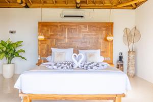 ペニダ島にあるMimpi Villas - Private Luxury & Romantic Villa with seaviewの木製のヘッドボードが付いた白いベッドのある寝室