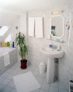 a white bathroom with a sink and a mirror at Auberge des Trois Châteaux in Eguisheim +26 photos