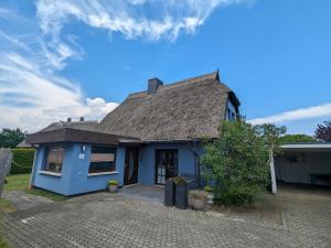 a blue house with a thatched roof at Dat smucke Reethus - EG in Born