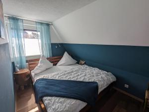 een kleine slaapkamer met een bed en een blauwe muur bij Dat smucke Reethus - OG in Born