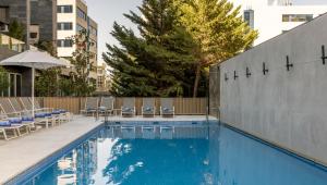a swimming pool with chairs and umbrellas next to a building at Ilunion Atrium in Madrid