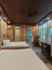 a bedroom with two beds and a desk and windows at Meeram Ganga, A Heritage Stay by the Ganges at Triveni Ghat in Rishīkesh