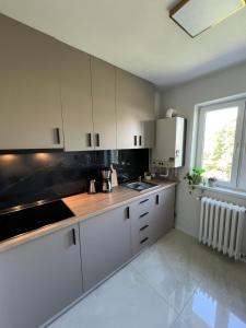 アルバ・ユリアにあるSunset Apartmentsの白いキャビネット、シンク、窓付きのキッチン