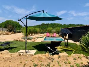 an umbrella and chairs next to a swimming pool at Le 007 Refuge -Rurale gîte élégant piscine privée in Queyssac