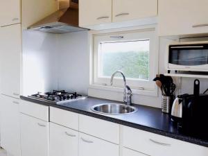 a white kitchen with a sink and a window at Inviting Dune Chalet in Hollum near Golf Course in Hollum