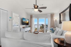 a living room with a white couch and a ceiling fan at Baywatch C10 in Pensacola Beach