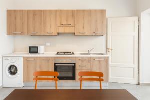 a kitchen with wooden cabinets and two orange chairs at Residenza del Capitano in Siena