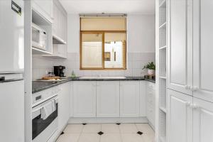 グレネルグにあるGlenelg Outlook - Beachfront Stay by Moseley Squareの白いキャビネットと窓付きの白いキッチン