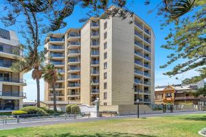 グレネルグにあるGlenelg Outlook - Beachfront Stay by Moseley Squareの高層アパートメントの建物で、正面に公園があります。